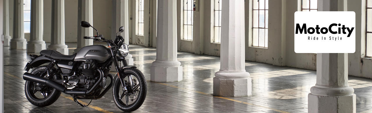 A brand-new Moto Guzzi V7 Stone 2025 is parked outside Motocity Daytona under the Florida sun.