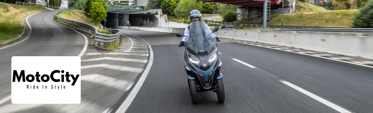 A three-wheel scooter displayed at MotoCity Motoplex, showing its sleek design and stability features.
